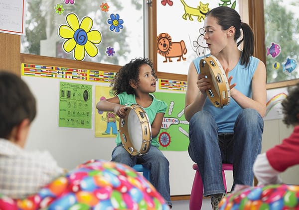 A music therapist plays the tambourine with a child in a group session.